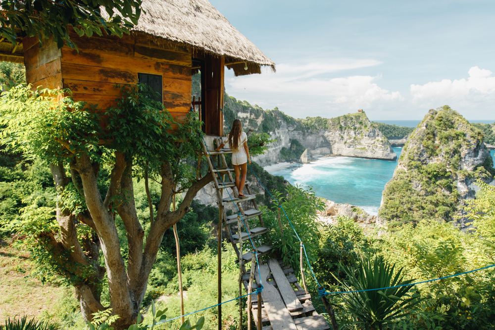 Young,Girl,On,Steps,Of,Traditional,House,On,Tree,,Look Eco-Friendly Travel