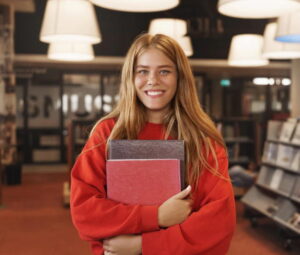 Ragazza che tiene in mano dei libri e sorride